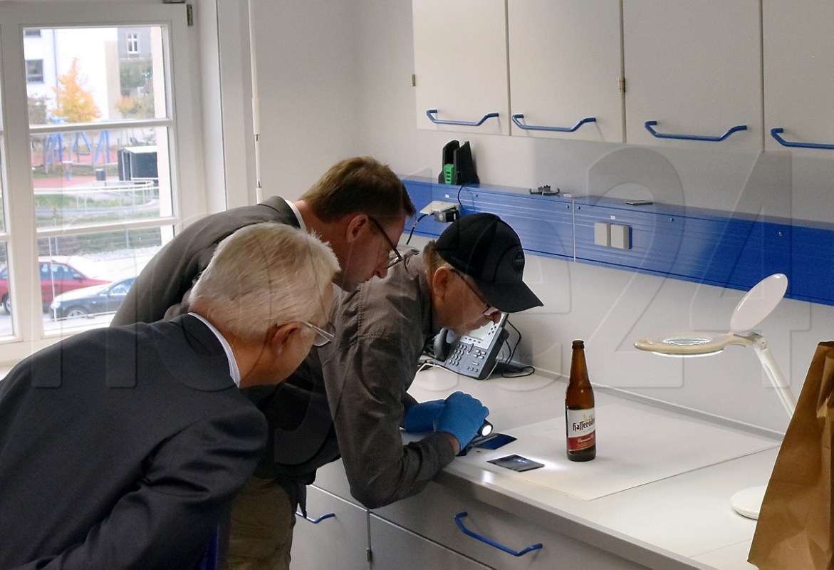 Sachsens Innenminister Roland Wöller schaute gestern in Hoyerswerda einem der Kriminaltechniker im neu eingerichteten Kriminaltechnischen Labor bei der Untersuchung einer Bierflasche genau auf die Finger. Foto: Uwe Schulz