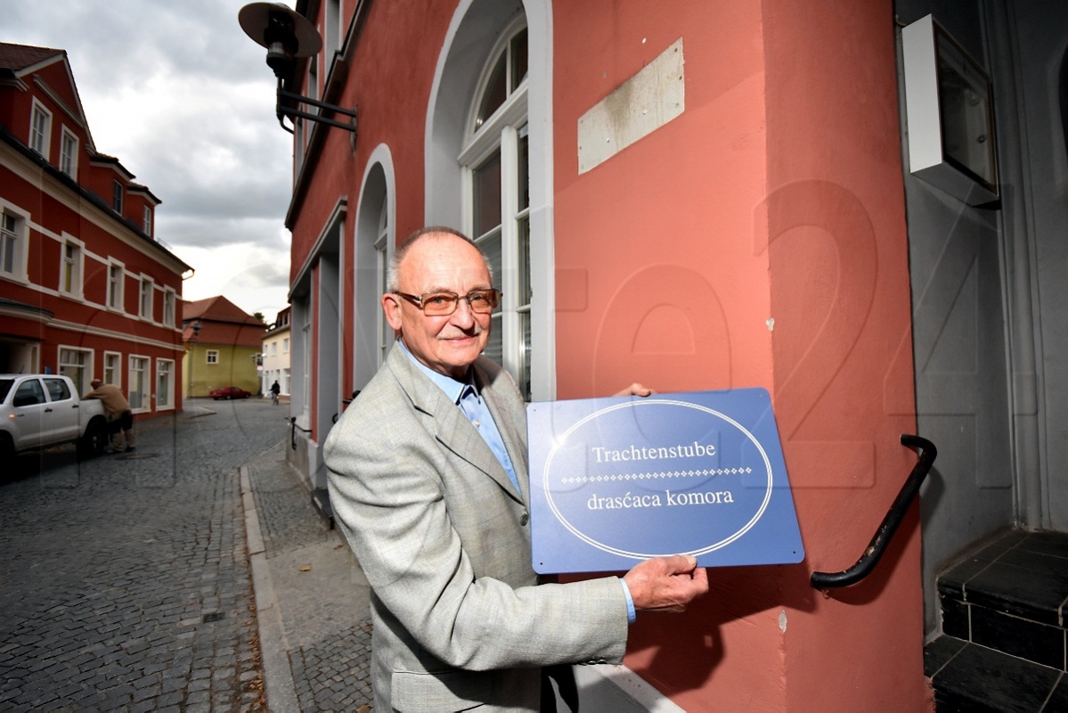 Werner Böhme bringt eines der beiden Schilder an der Trachtenstube an. Foto: Uwe Schulz