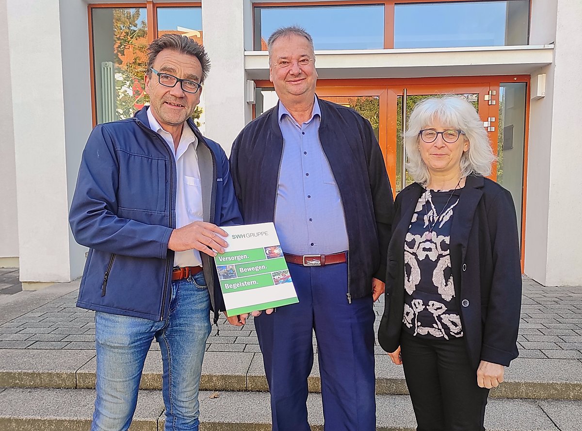 Man sieht Lausitzhallen-Geschäftsführer Dirk Rolka, Holger Günther vom Schulförderverein des Lessing-Gymnasiums und Schulleiterin Lubina Kühne vor der Schule.