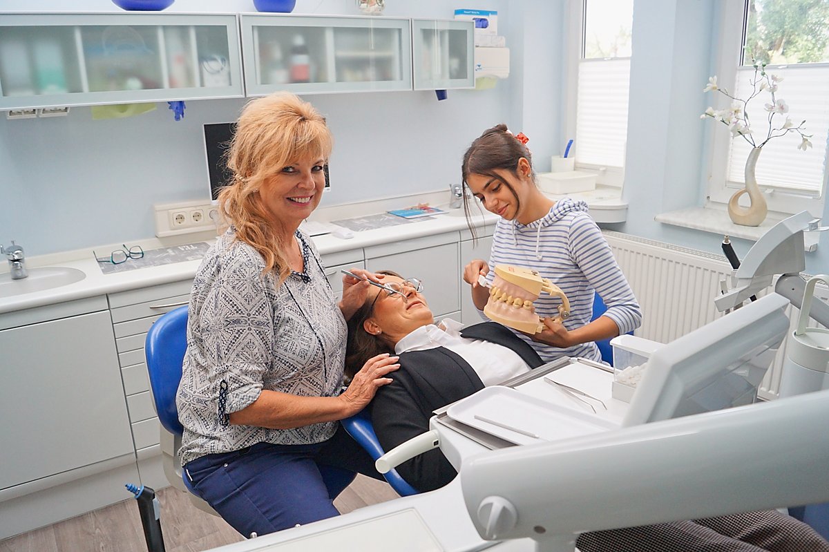Man sieht Zahnärztin Dr. Sibylle Liebmann und ihre Auszubildende Emely Albrecht bei der Behandlung einer Patientin.