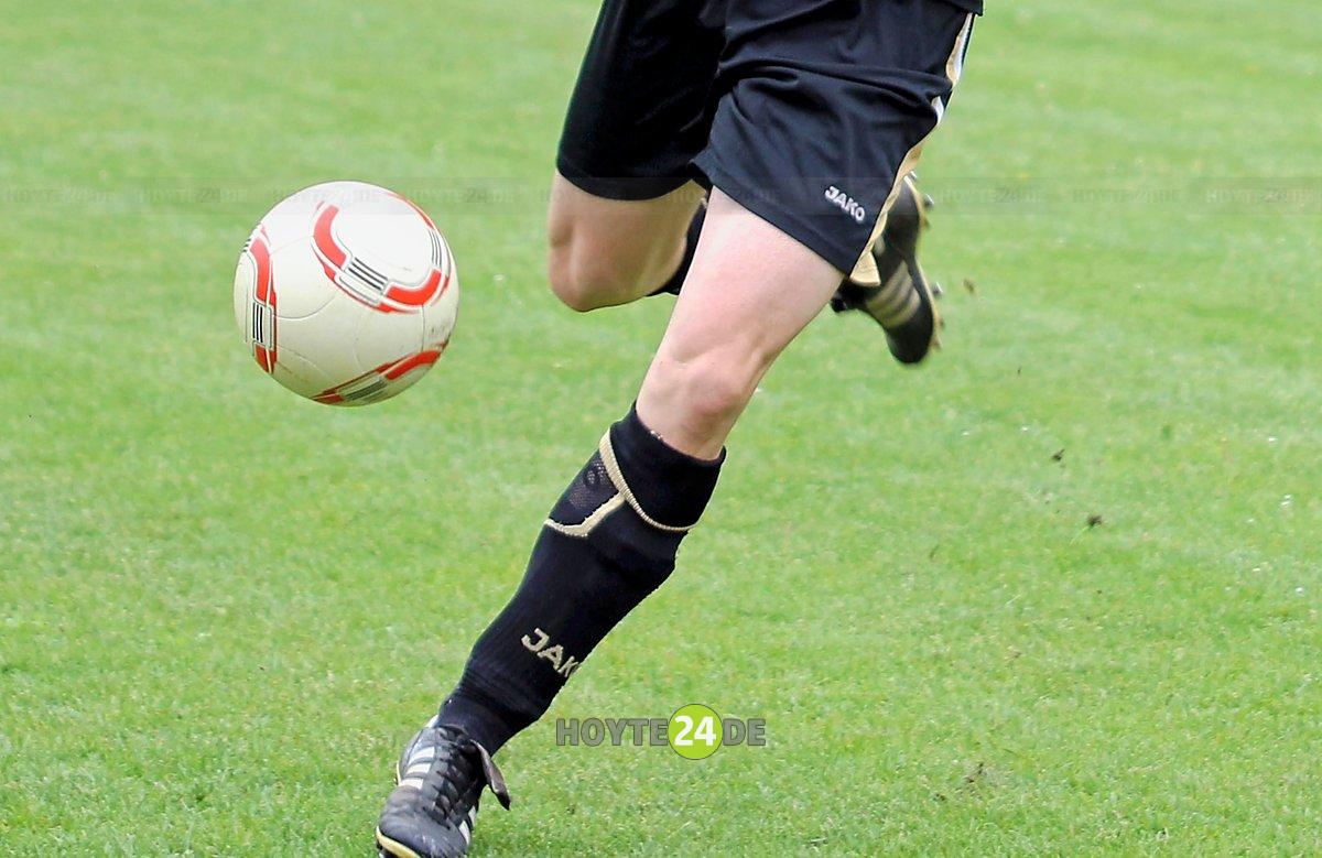 Man sieht einen Fußball und zwei Fußballerbeine.