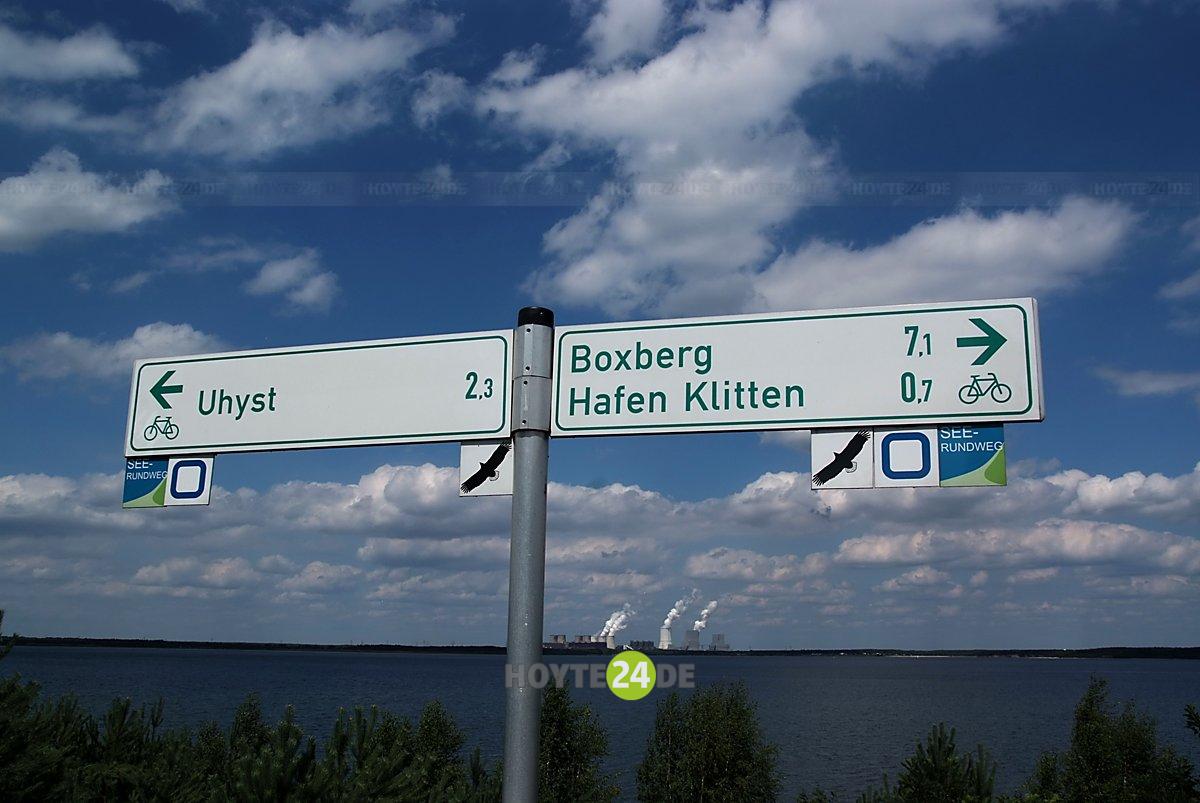 Man sieht Radwegweiser nach Uhyst und Boxberg sowie den Bärwalder See.