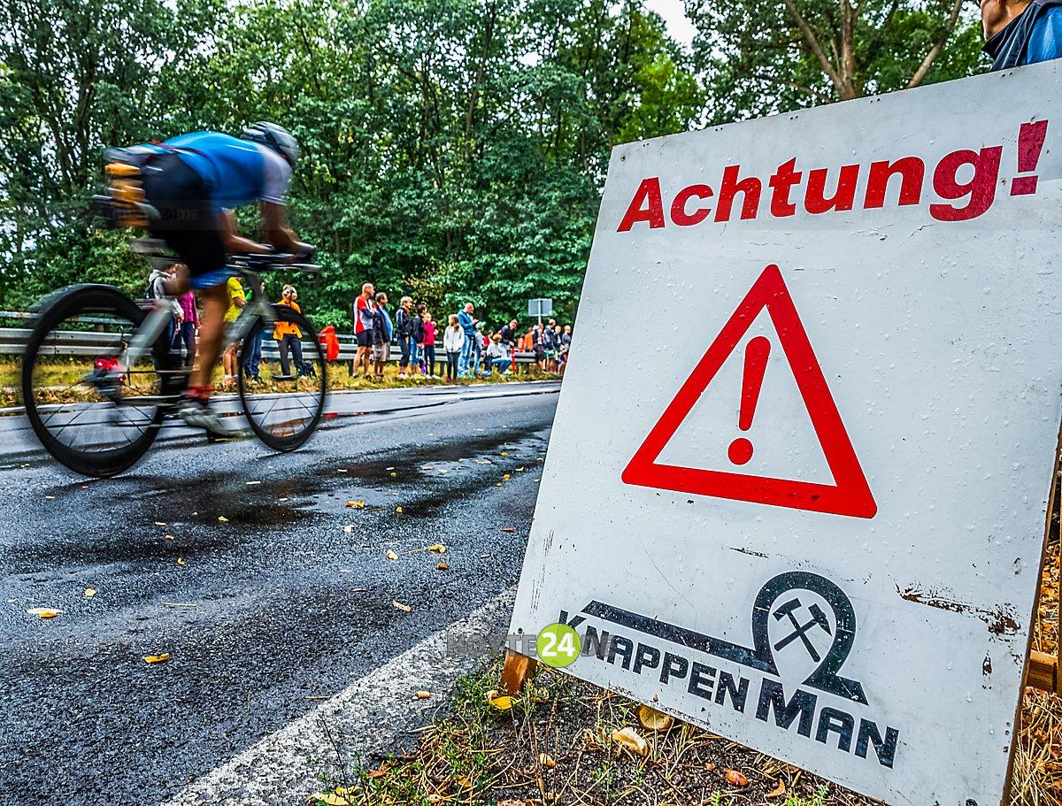 Man sieht einen Radfahrer und ein Schild mit der Aufschrift Achtung, Knappenman.