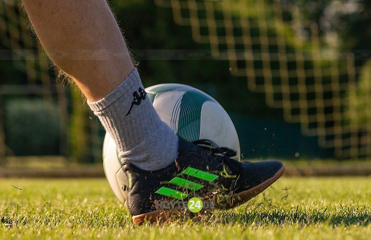 Man sieht einen Fußball, einen Fuß und ein angedeutetes Tornetz.