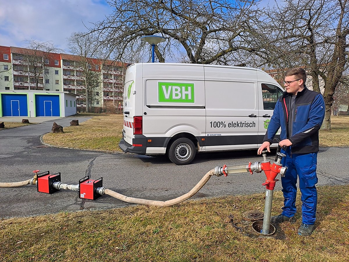 Man sieht VBH-Netzmonteur Dominik Winter, wie er den Aufbau einer Rohrnetzspülung an einem Hydranten im Wasserwerk demonstriert.