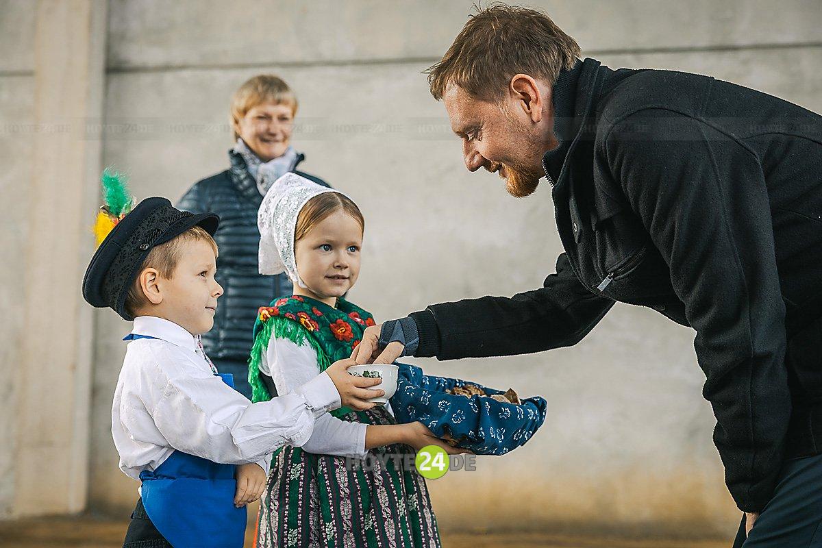 Man sieht Ministerpräsident Michael Kretschmer, wie ihn Kinder aus der Kita Krabat mit Brot und Salz begrüßen.