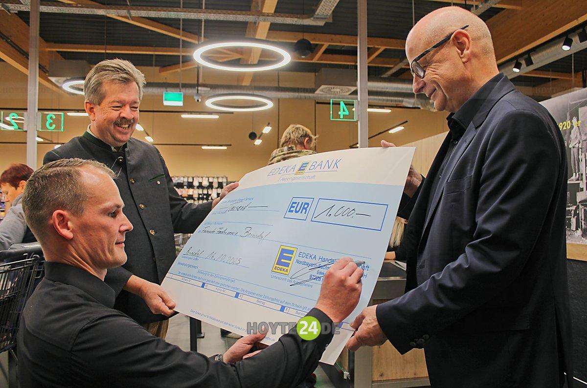 Man sieht René Schäfer beim Unterzeichnen eines symbolischen 1.000-Euro-Spenden-Schecks.