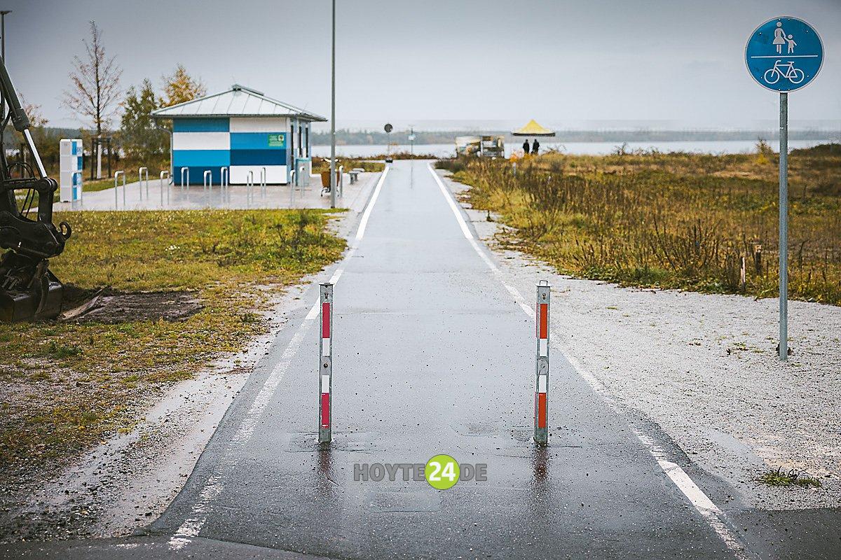Man sieht den Weg zum See und das Sanitärhäuschen.