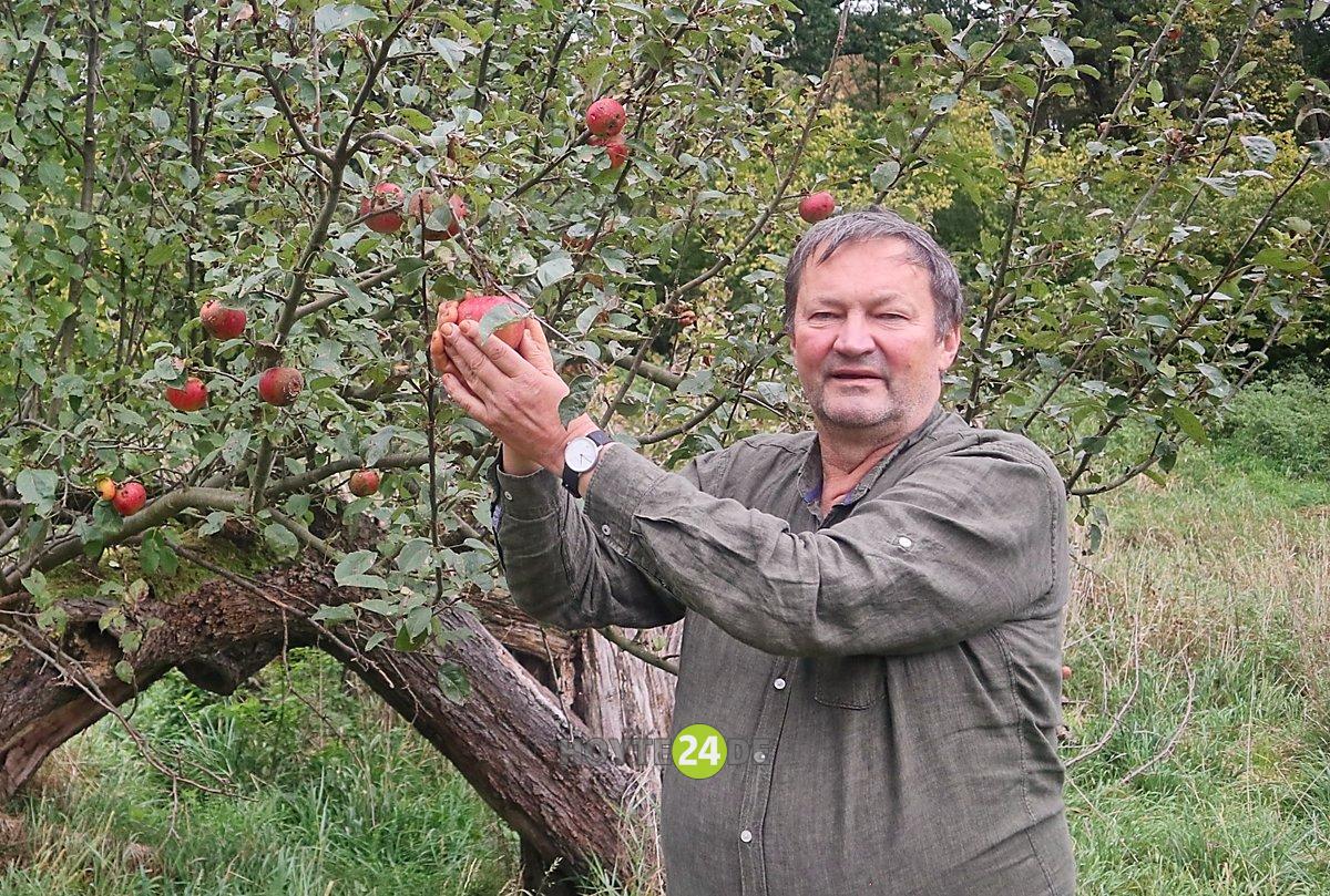 Man sieht Christoph Schuster mit einem Apfelbaum.