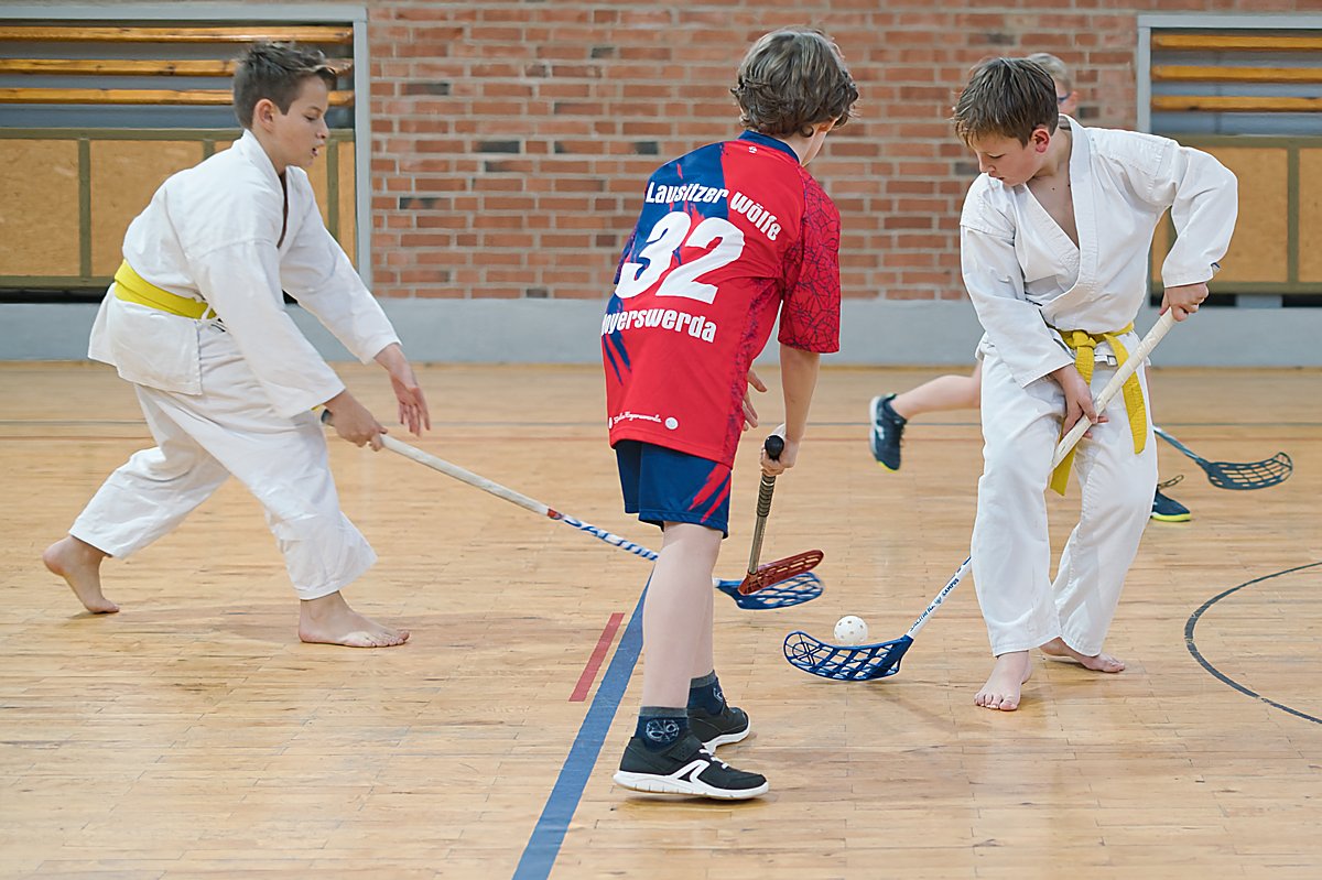 Man sieht Karateka und einen Floorballer vom Verein Karate-Do Hoyerswerda beim Floorballspeiel.