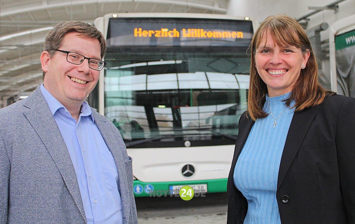 Man sieht Stefan Löwe und Sandra Trebesius vor einem Bus mit der Aufschrift Herzlich willkommen.