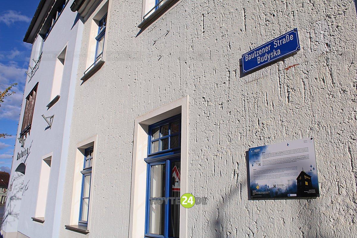 Man sieht Wittichenaus Rathaus mit dem Krabat-Weg-Schild.