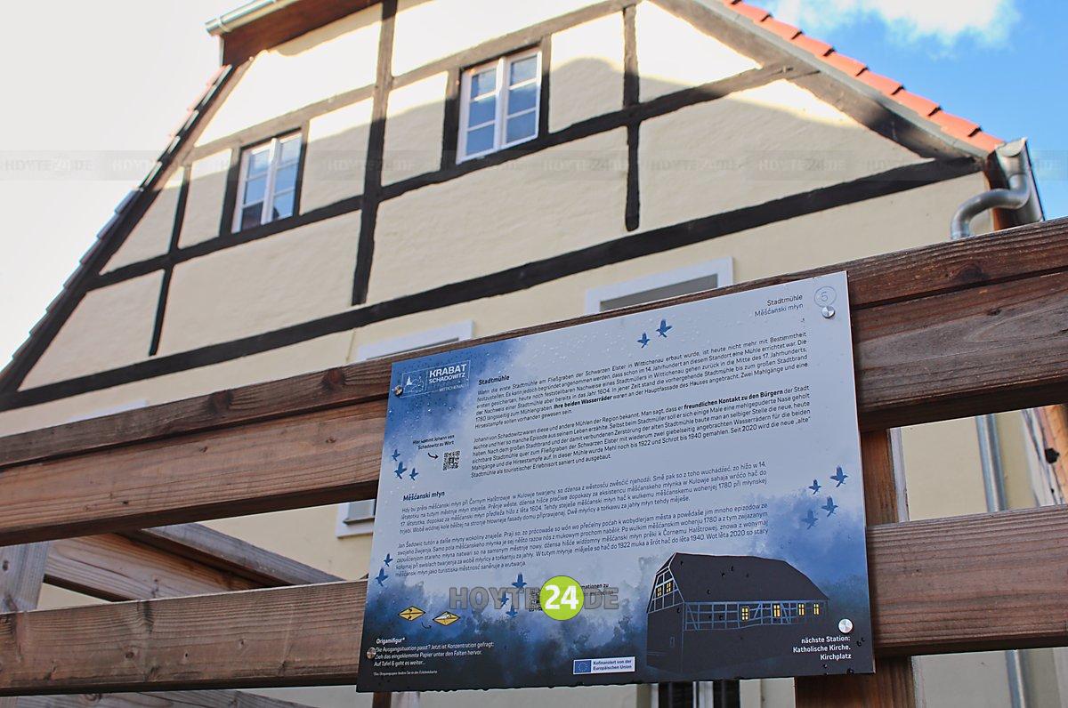 Man sieht die Stadtmühle Wittichenau mit dem zugehörigen Schild der Krabat-Erlebnistour.