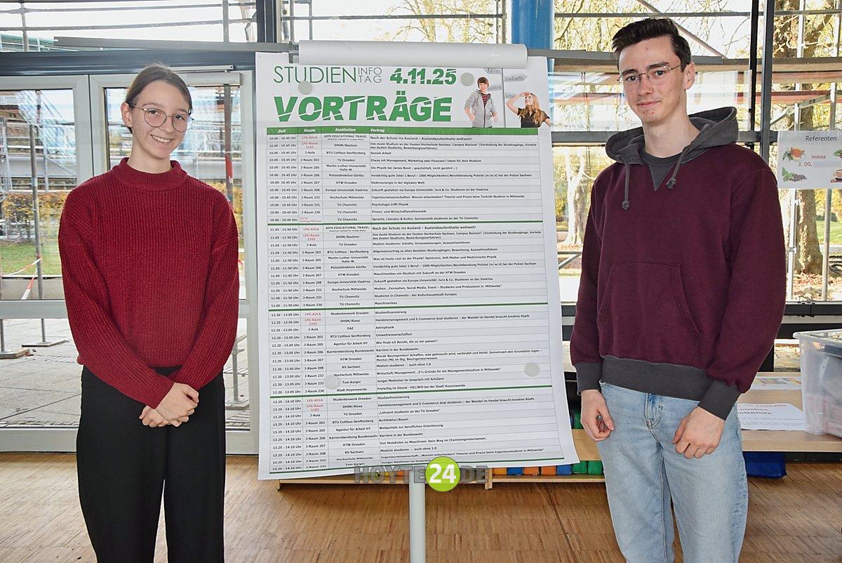 Man sieht Sophie Schüler und Jonas Kandziora vor einem Plan mit Vorträgen zum Studieninformationstag.