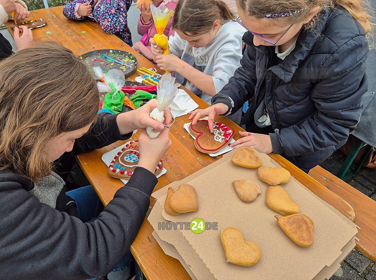 Man sieht Kinder beim Verzieren von Pfefferkuchen,