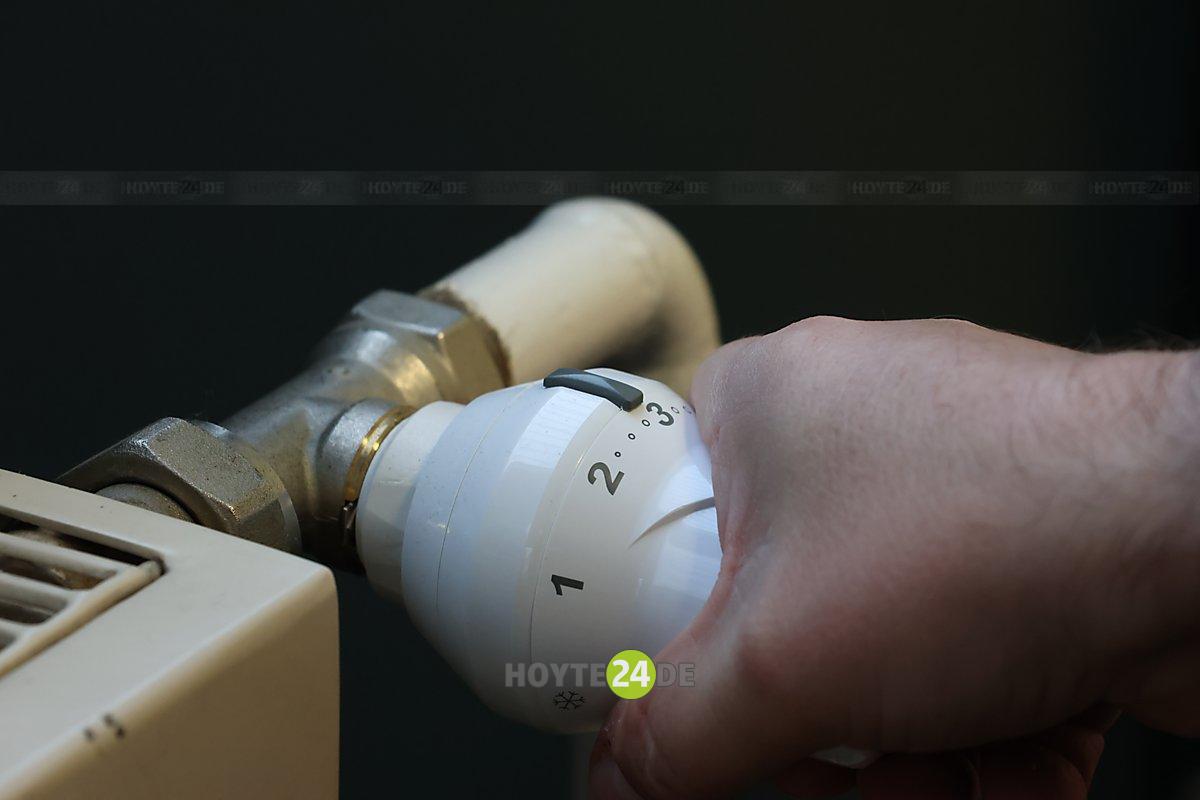 Man sieht eine Hand an einem Heizungsknopf.