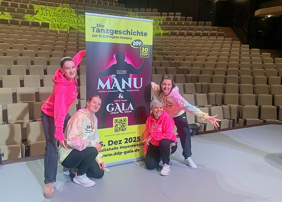 Man sieht vier Tänzerinnen und ein Plakat für die Veranstaltung in der Lausitzhalle