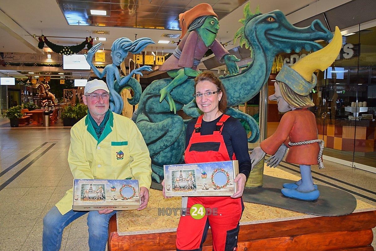 Hinter Clemens Bresan und Madeleine Matschke mit den Stollenverpackungen steht die neue Holzfigurengruppe des polnischen Künstlers Sylwester Chlodzinski.