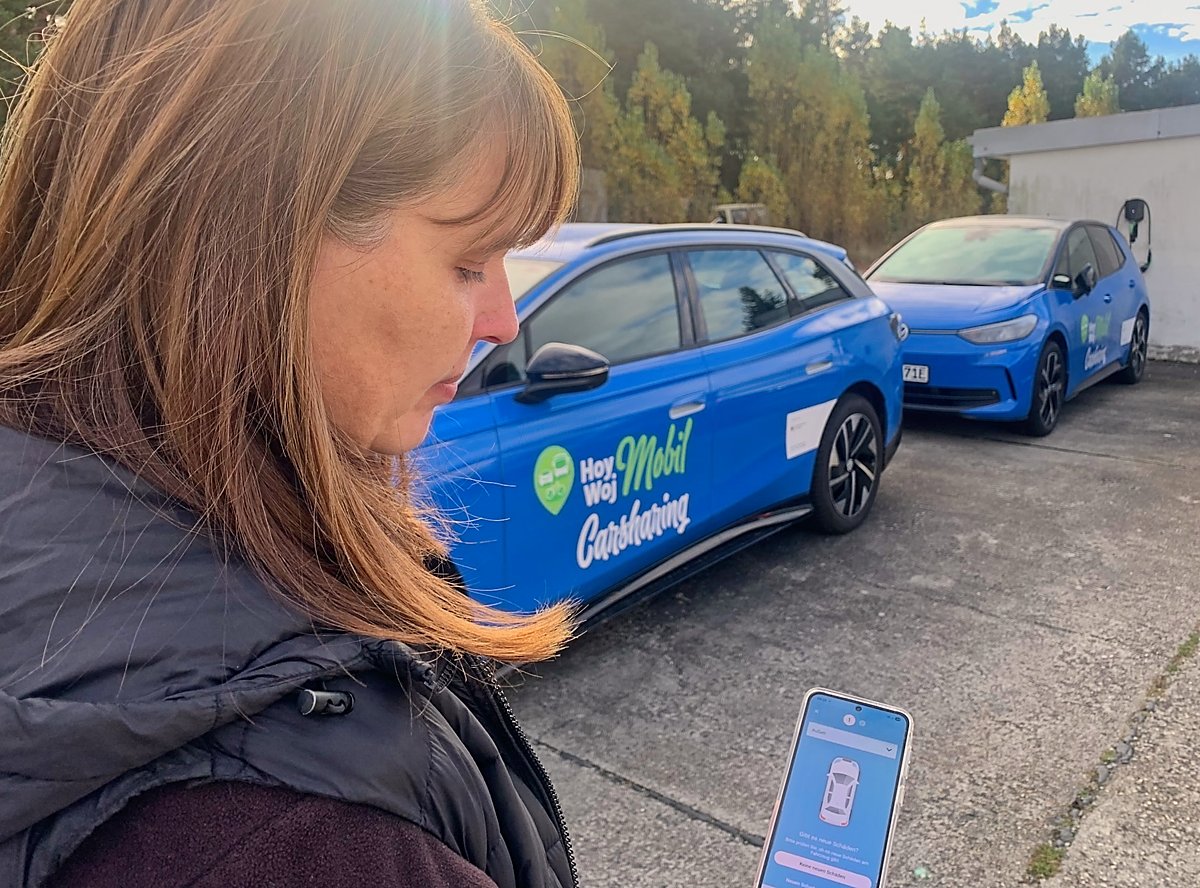 Man sieht Sandra Trebesius mit Autos und Mobilfunkapp.