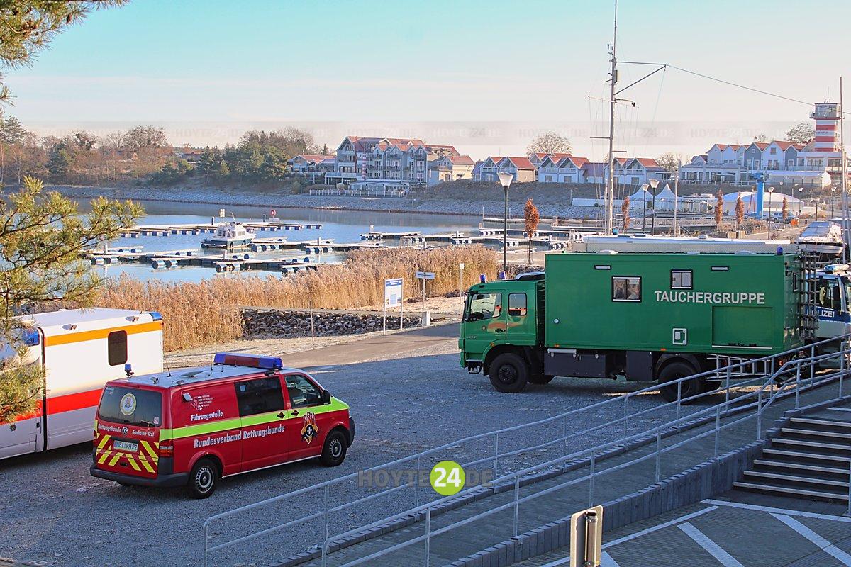 Man sieht einen Krankenwagen, einen Rettungshunde-Transporter und einen Transporter Tauchergruppe am Geierswalder See.