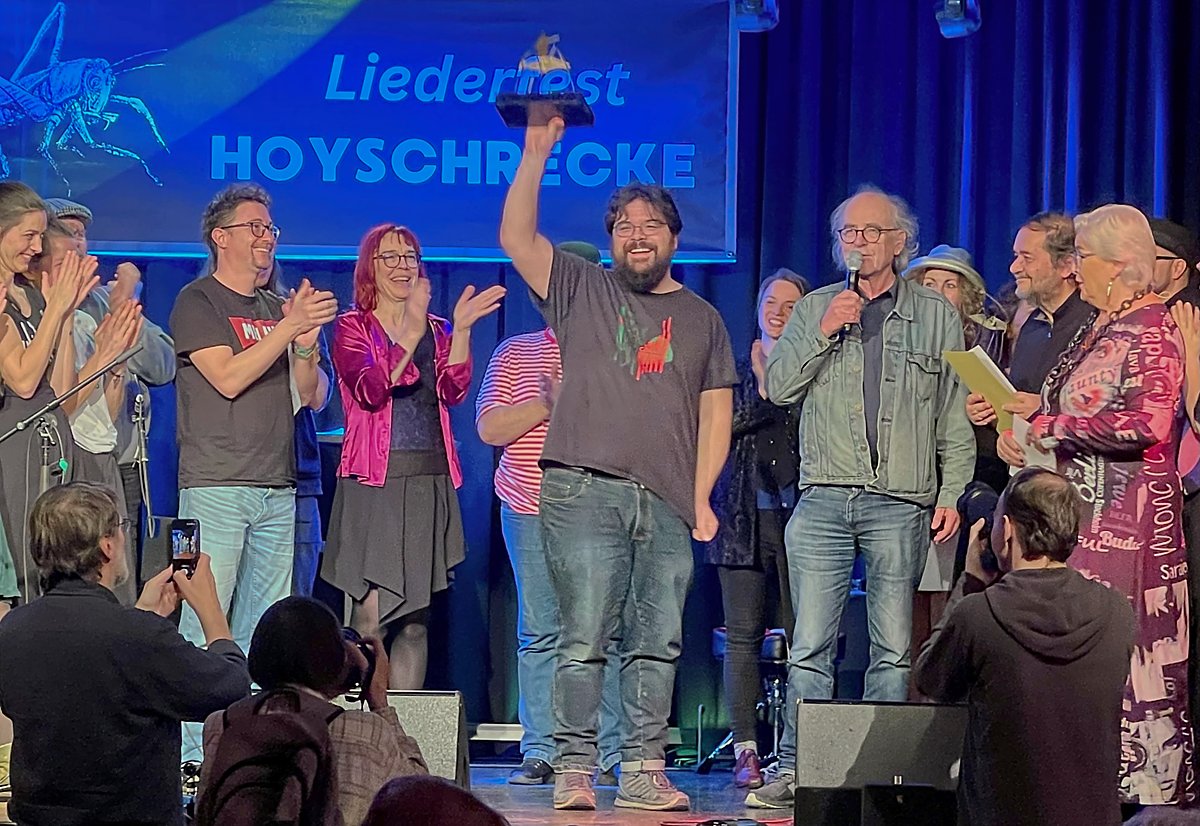 Man sieht Hoyschrecken-Gewinner Paul Geigerzähler seinen Preis in die Luft recken.