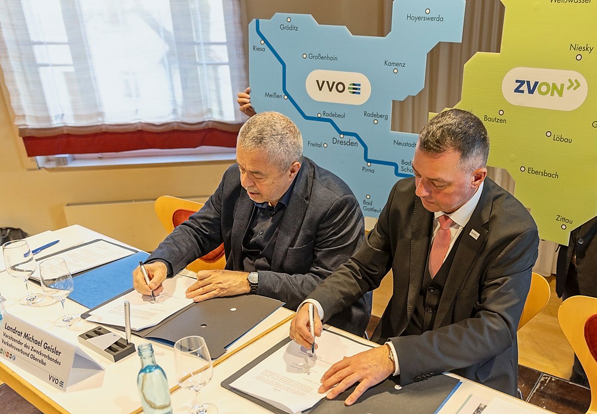 Man sieht die Landräte Michael Geisler und Udo Witschas bei der Unterzeichnung des Vertrages über den neuen Zweckverband Verkehrsverbund Ostsachsen.