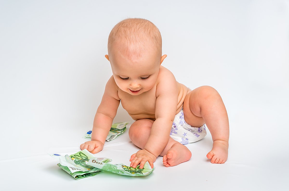 Man sieht ein Baby mit Geld.