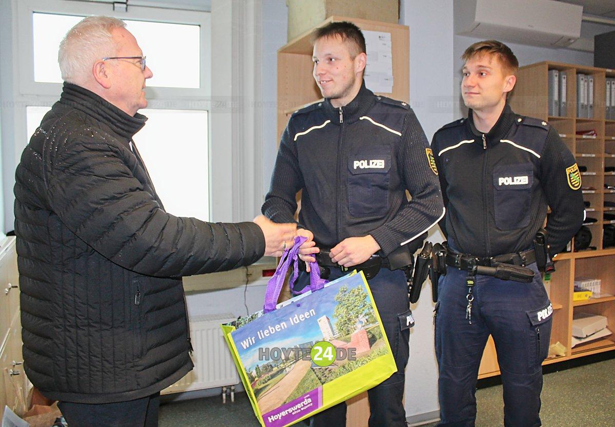 Man sieht Oberbürgermeister Torsten Ruban-Zeh bei der Übergabe eines Präsentes an die Polizeikommissare Tim Wende und Johannes Moschke.