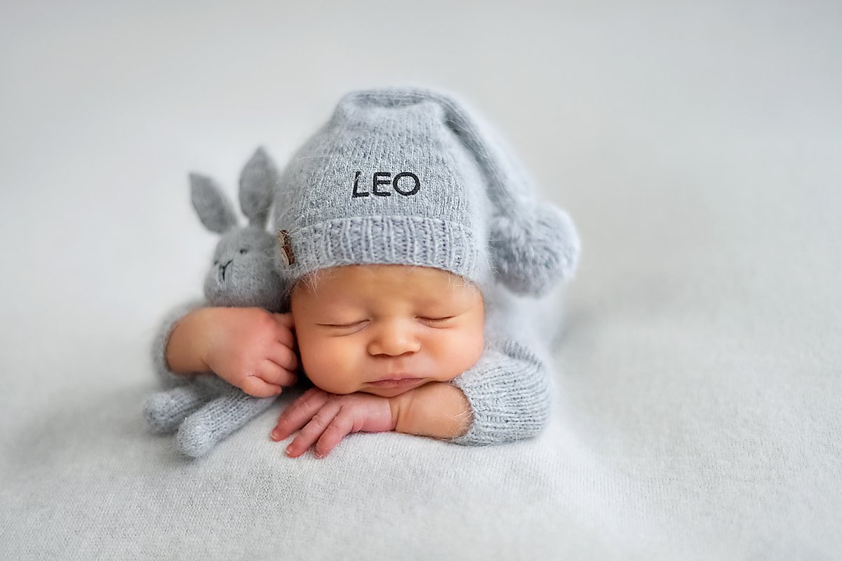 Man sieht ein Baby mit einer Mütze, auf der der Name Leo steht.