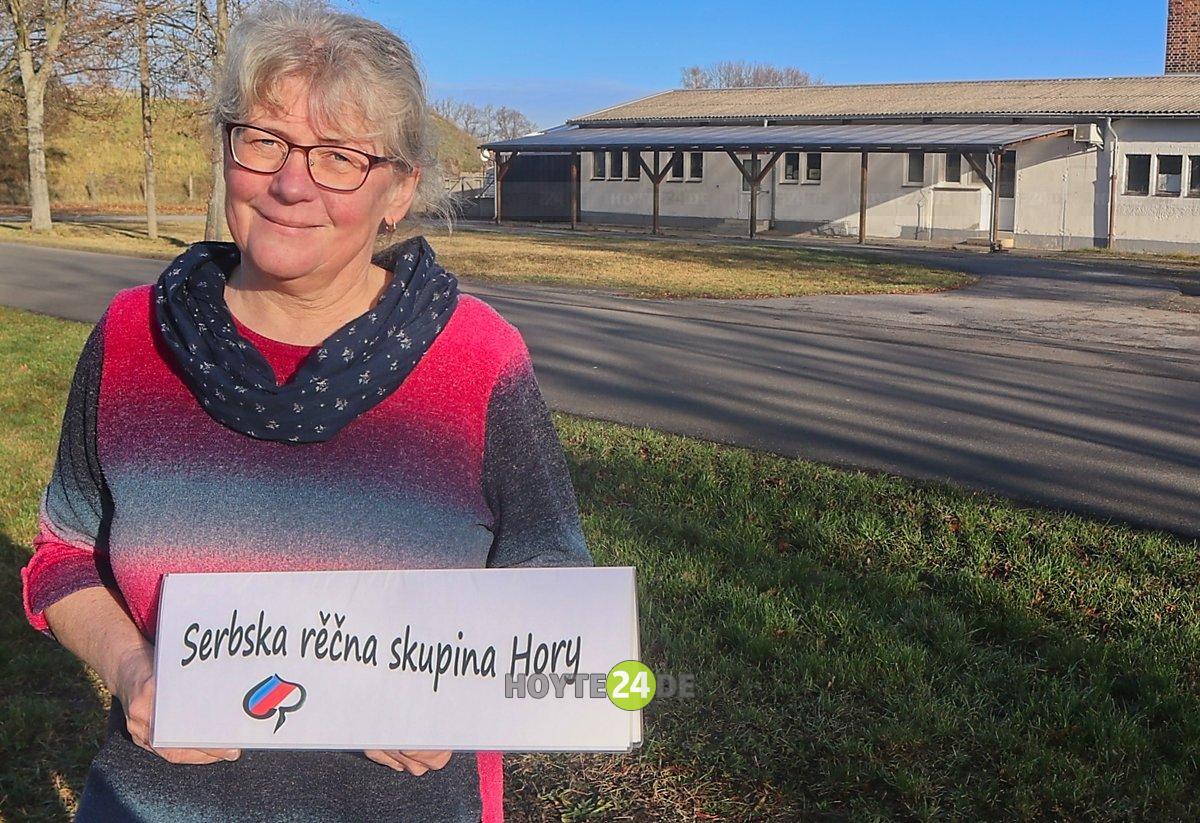 Man sieht Christina Fabian mit einem Schild Sebska recna skupina Hory - Sorbische Sprachgruppe Bergen.