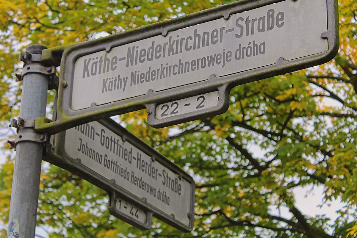 Man sieht die Straßenschilder Käthe-Niederkirchner-Straße und Johann-Gottfried-Herder-Straße.