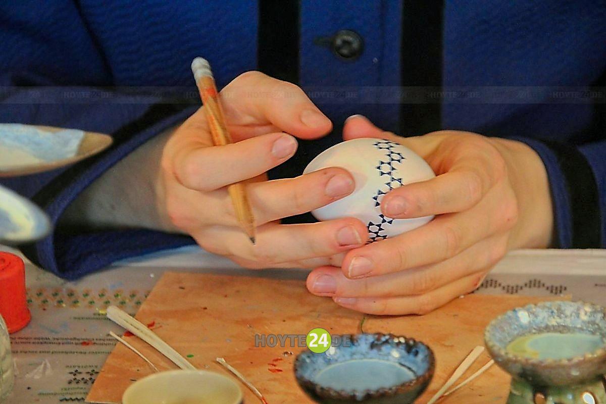 Man sieht Hände von jemandem, der ein Osterei mit sorbischen Motiven gestaltet.