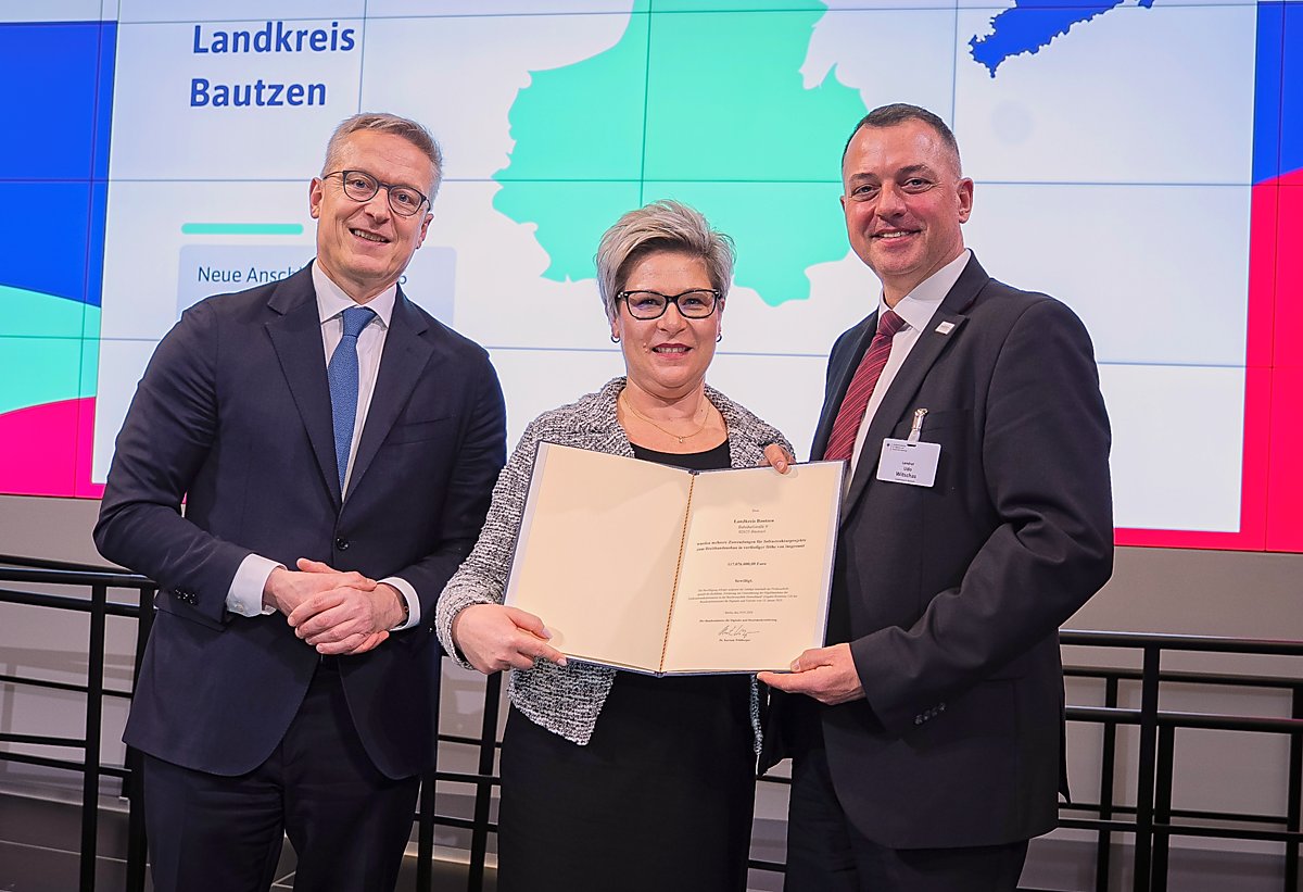 Man sieht Karsten Wildberger, Romy Reinisch und Udo Witschas mit dem Fördergeldbescheid.