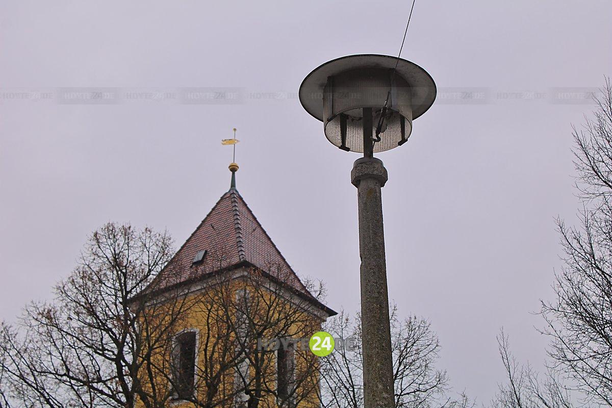 Man sieht eine Straßenlaterne neben der Kirchturmspitze von Lohsa.